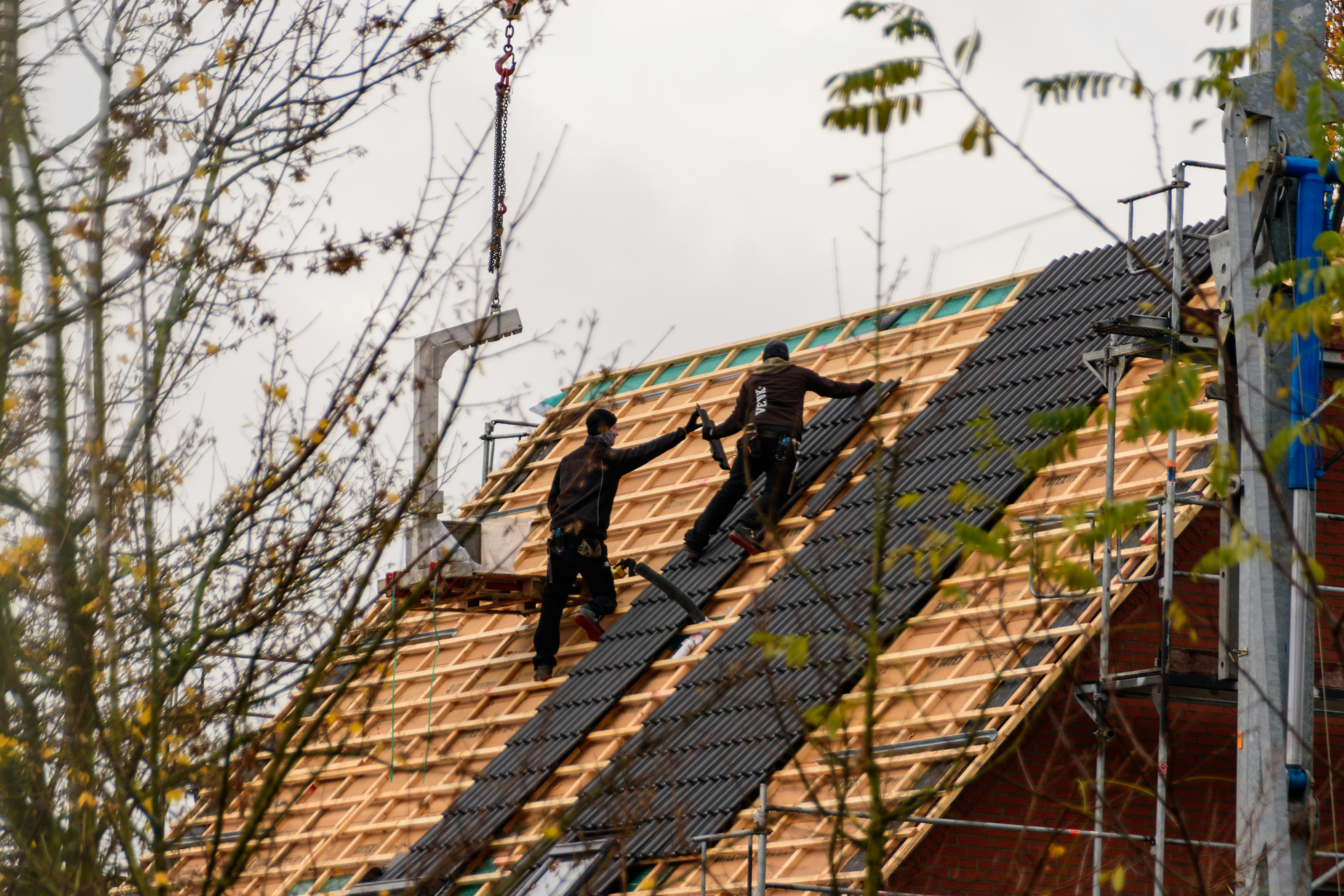 Construction workers installing roofing materials on a house.
